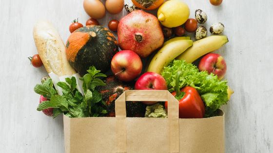 Verschiedene Lebensmittel in einer Papiertüte: Obst, Gemüse, Eier und Brot