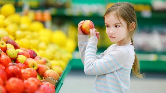 Mädchen hält skeptisch einen Apfel in der Hand