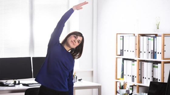 Frau macht Rückenübung im Büro