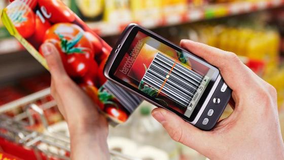 Smartphone mit Barcode-App vor Tomatensaftpackung