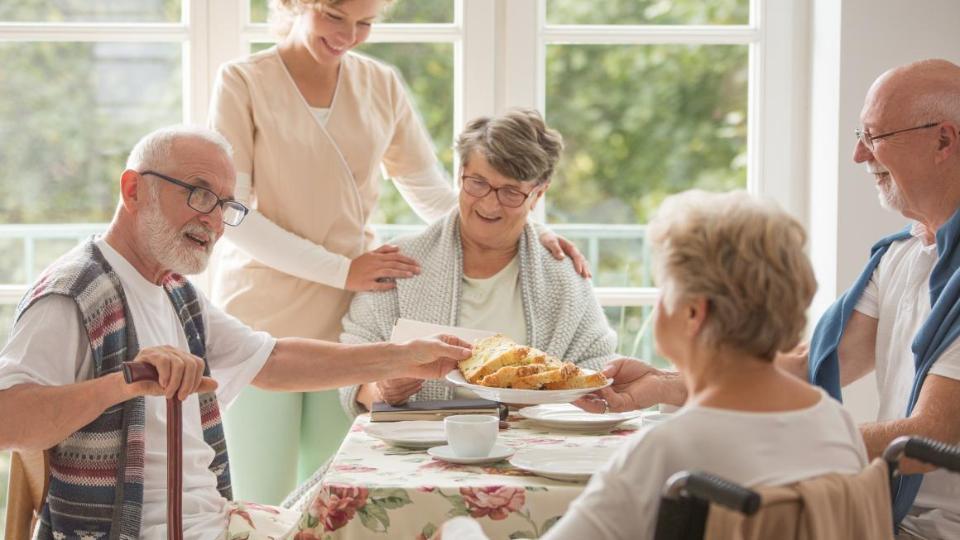 Zwei Seniorinnen und zwei Senioren nehmen in Betreuung eine Mahlzeit zu sich
