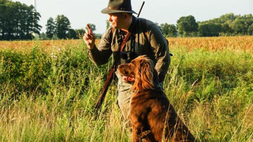 Jäger mit Hund vor Getreidefeld