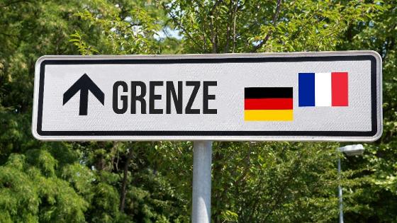 Schild welches den Schriftzung "Grenze" und den Flaggen von Deutschland und Frankreich abbildet