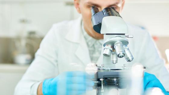 Ein junger Forscher im Labor schaut in ein Mikroskop