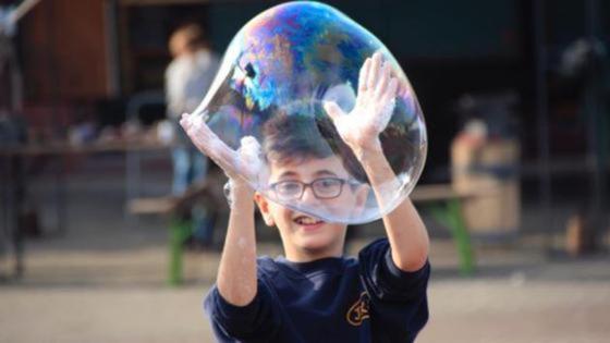 Ein Junge spielt mit einer großen Seifenblase