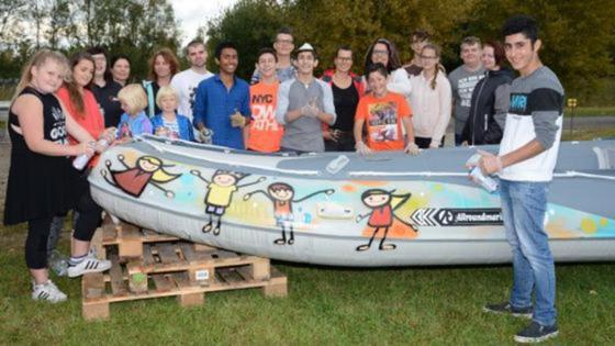 Projektteilnehmer stehen um ein selbst gestaltetes Schlauchboot herum 
