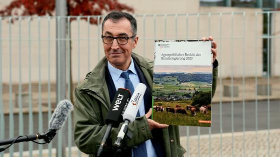 Bundesminister Cem Özdemir hält den Agrarbericht 2023 in die Kamera
