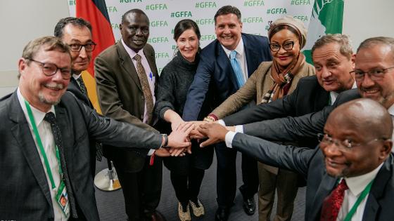 Neun Personen halten in der Mitte ihre Hände übereinander, darunter Bundesminister Özdemir und Josefa Sacko, Kommisarin der Afrikanischen Union 