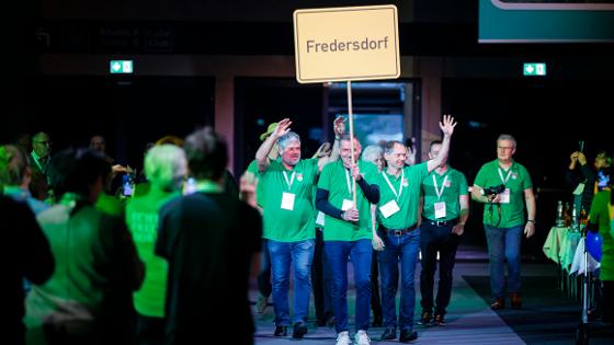 Vetreterinnen und Vertreter der Gemeinde Fredersdorf laufen in die Halle ein, in der Hand wird eine Tafel mit der Aufschrift "Fredersdorf" getragen