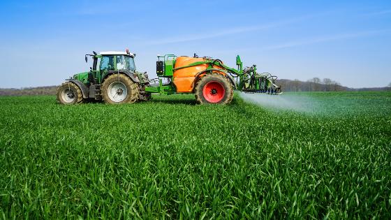 Ein Traktor mit einer Pflanzenschutzspritze auf einem Getreidefeld