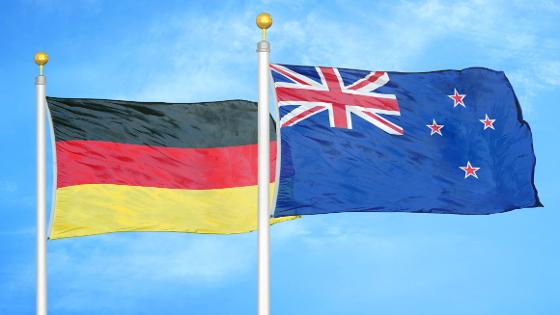 die neuseeländische und die deutsche Flagge wehen vor blauem Himmel