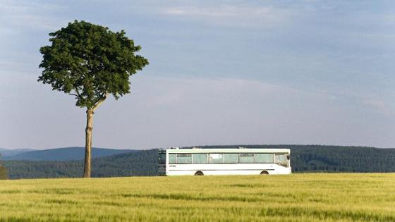 A bus passes a field in the country.